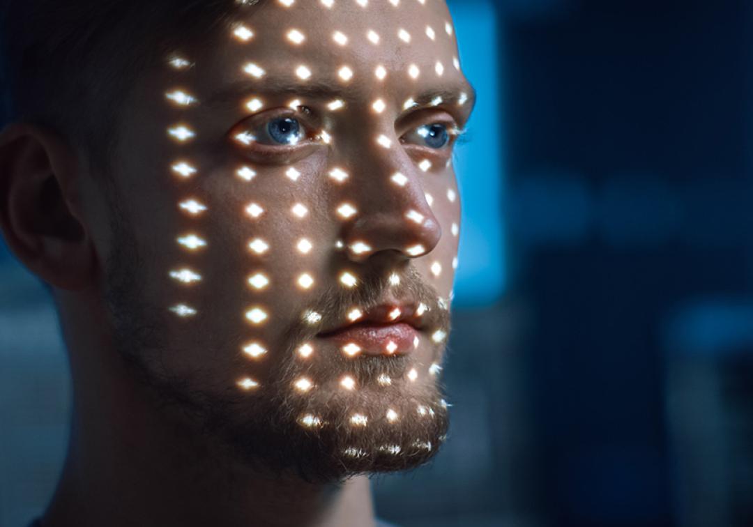 A man's face illuminated by patterns of light.