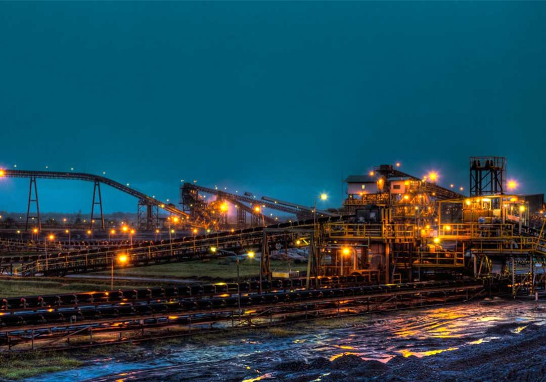 Long shot of a coal mine lit up with bright lights at night time.