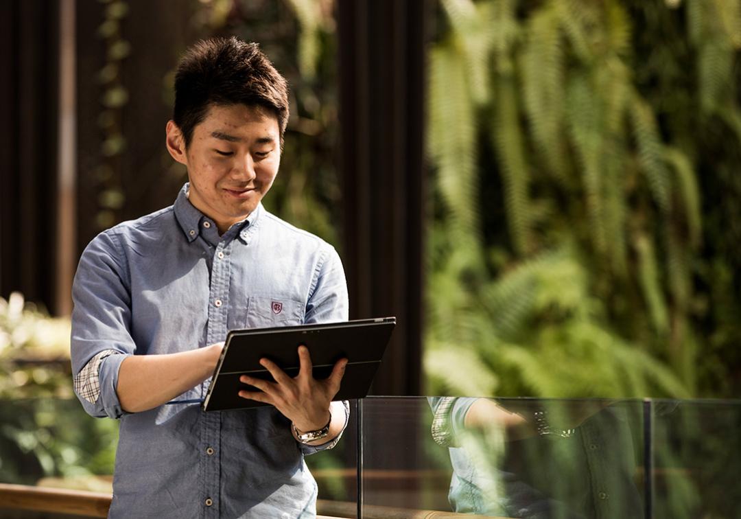 A man walking and using an iPad.