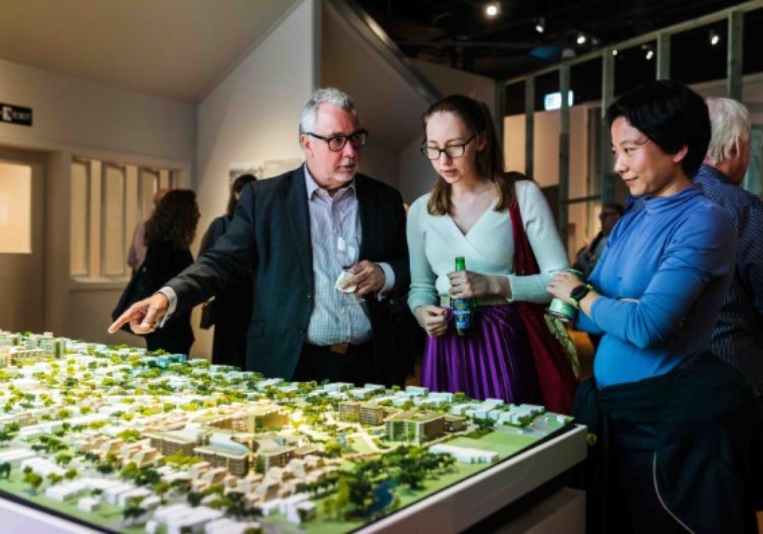 People review an architectural model at an exhibition 