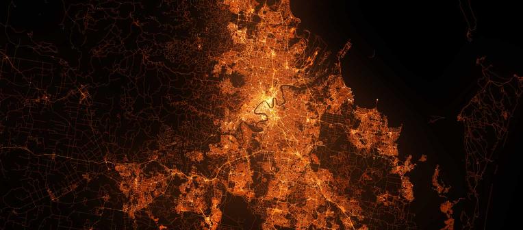 Aerial view of Brisbane city and surrounding suburbs, lit up at night by a network of bright lights