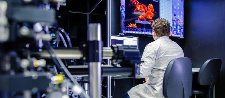 UQ researcher examines medical models on a computer, surrounded by silver equipment