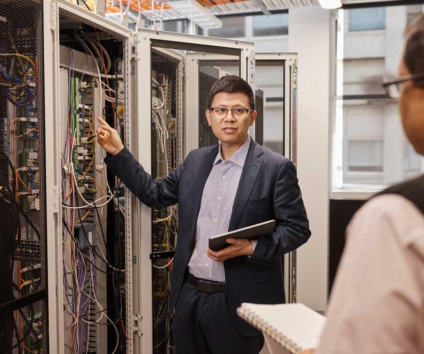 An observer looks on as a UQ expert explains a complex series of interconnected wires