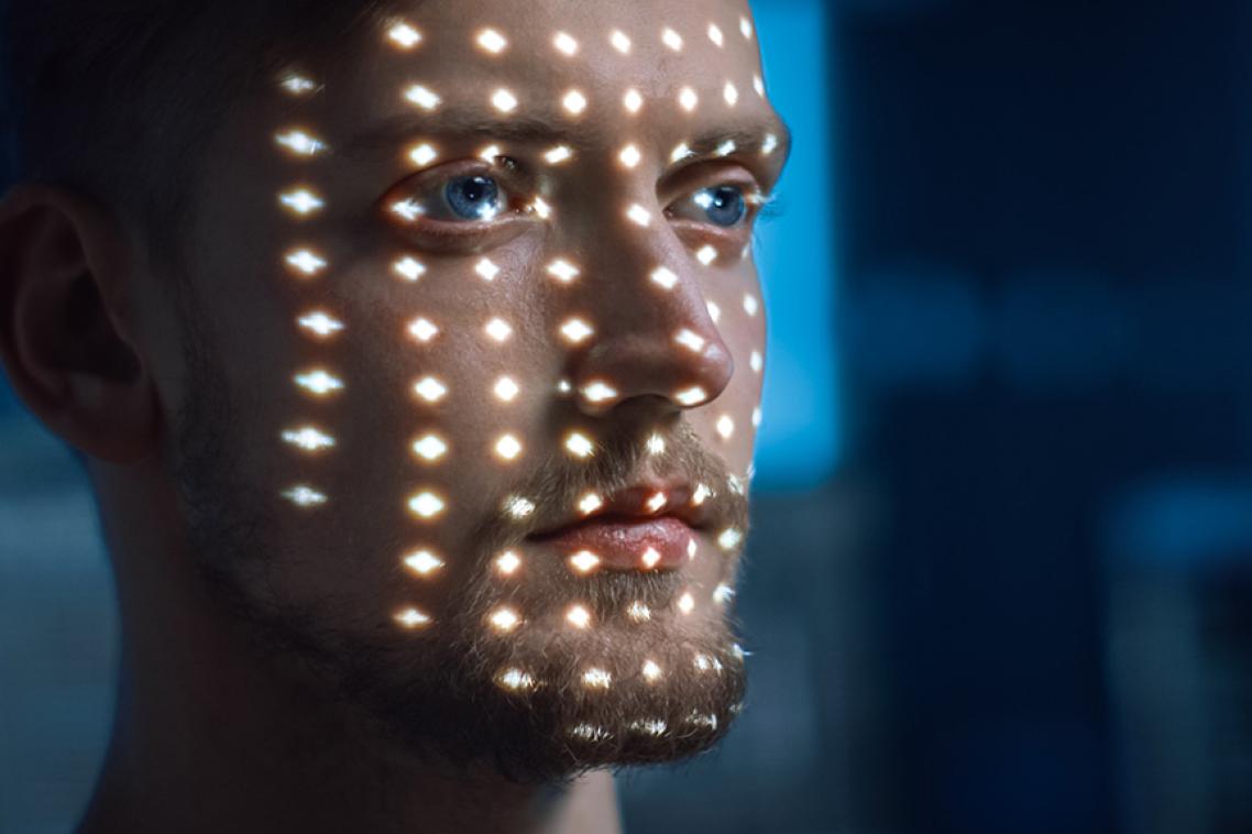 A man's face illuminated by patterns of light.