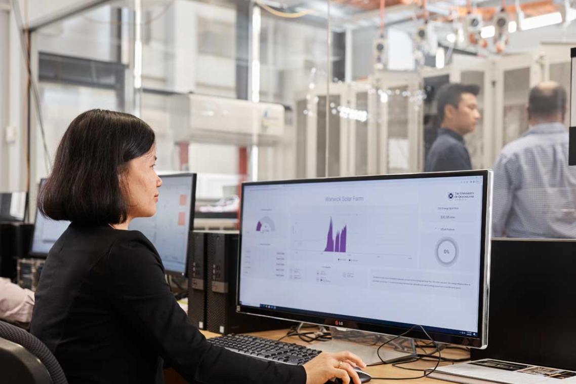 UQ expert monitors graphs on a computer while colleagues investigate equipment in a neighbouring room