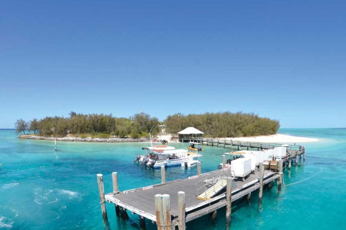 Extreme long shot of Heron Island research station, showing a boat moored off a long jetty in the Great Barrier Reef.