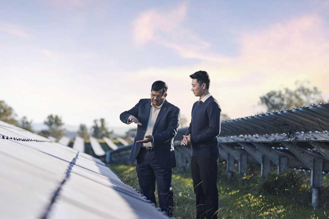 2 UQ researchers assessing a row of solar panels on a sunny day at one of our solar farms