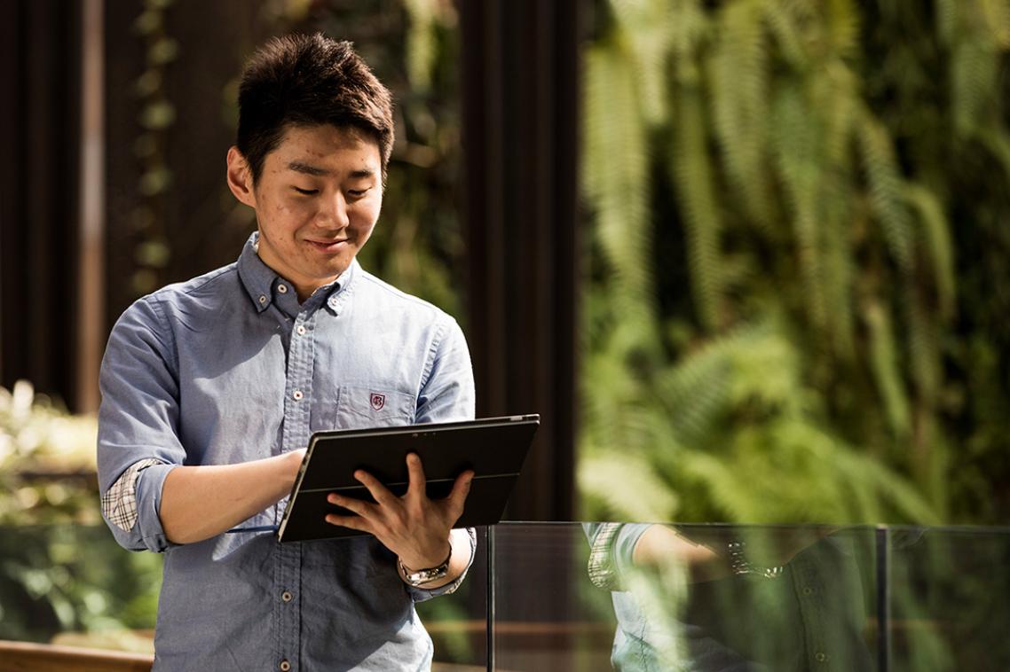 A man walking and using an iPad.