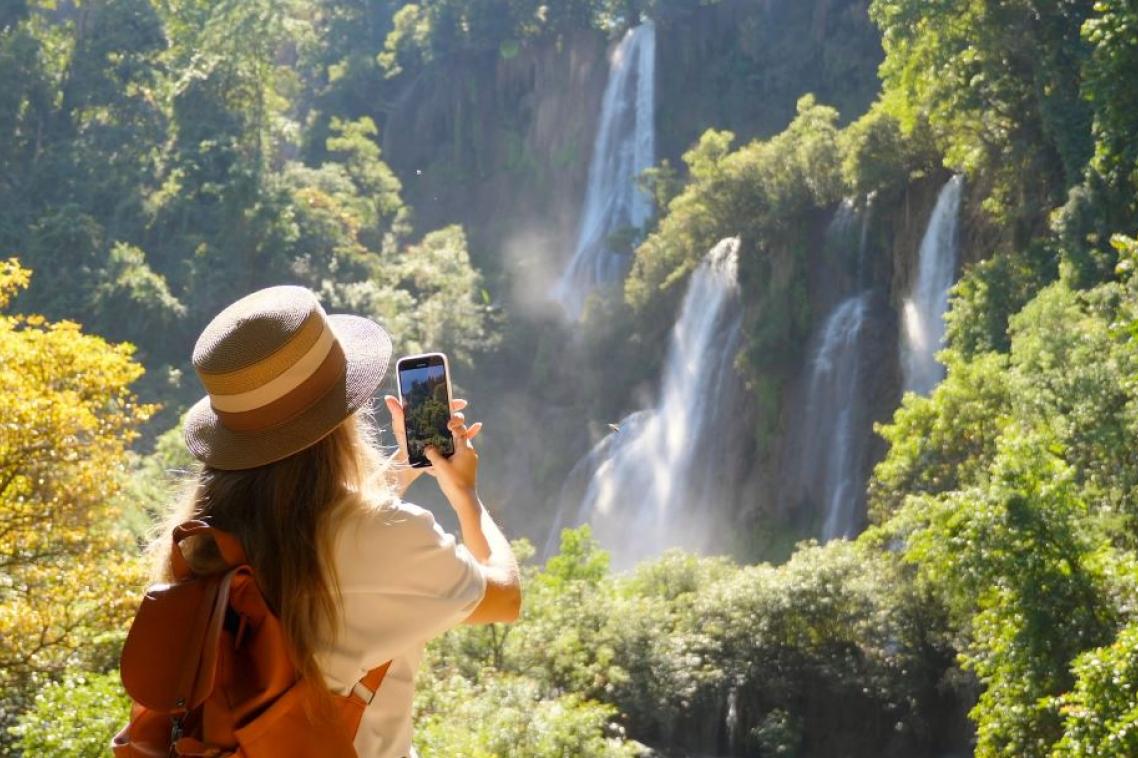 A woman takes a photo of waterfalls on her phone