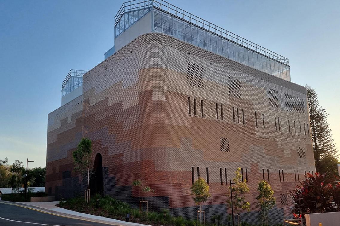 The exterior of the Plant Futures Facility, a large brick building with glasshouses on its roof.