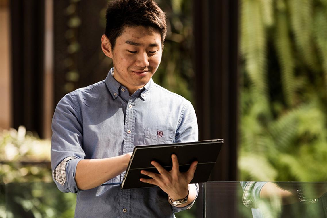 Man holding laptop with green wall in backrgound
