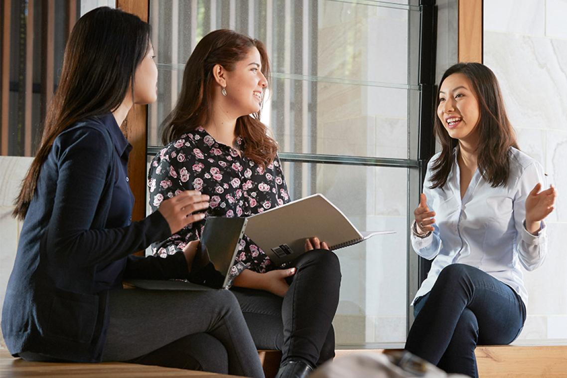 Three women seated ina meeting with laptops
